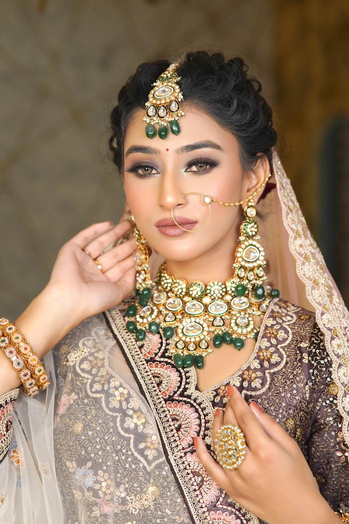 A bride adorned with traditional Indian jewelry and attire in a graceful pose.